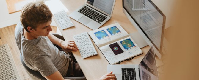 Man working from home with multiple laptops and monitors