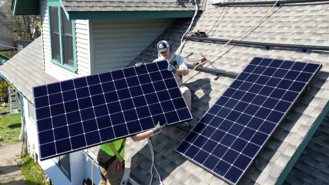 Technicians installing solar panels on a residential roof