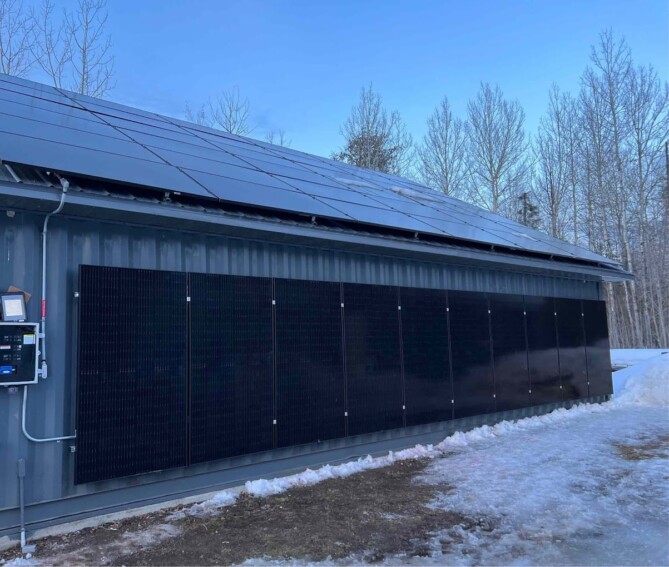 Solar panel installation on the side and roof of a building in winter, completed by Wolf River Electric, enhancing energy efficiency year-round.
