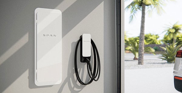 SPAN electric panel and EV charger mounted on a wall in a modern garage.