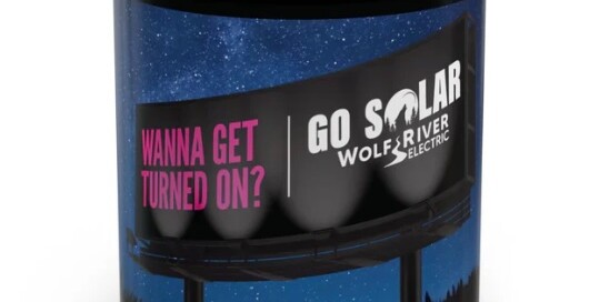 Black coffee mug featuring Wolf River Electric's 'Wanna Get Turned On?' slogan with a vibrant night sky and solar billboard design.