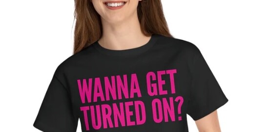 Trendy black crop top with bold pink 'Wanna Get Turned On?' slogan by Wolf River Electric, promoting solar energy in style.