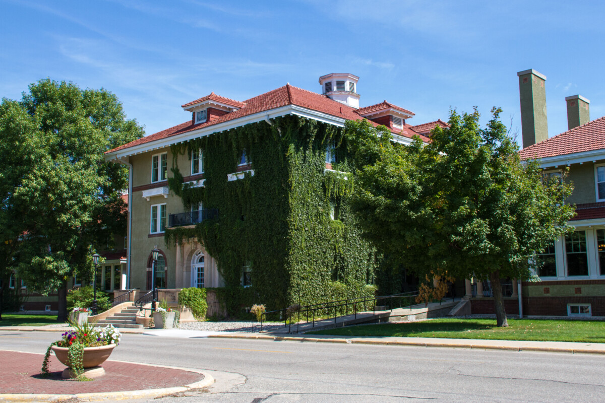 Historic ivy-covered building with red tile roof in Willmar, Minnesota, surrounded by trees and landscaping on a sunny day A corner shot of a building covered in ivy during the day in Willmar, Minnesota.