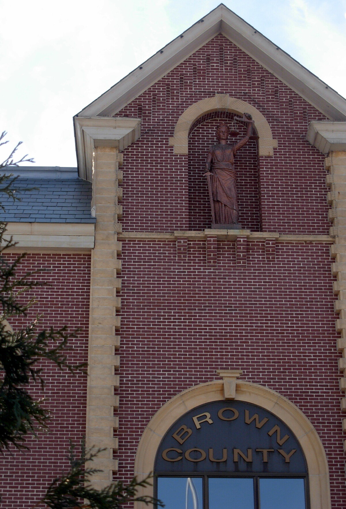 Zoomed in shot of a bronze statue of a woman on the front of the Brown County Courthouse in Brown County, Minnesota during the day.