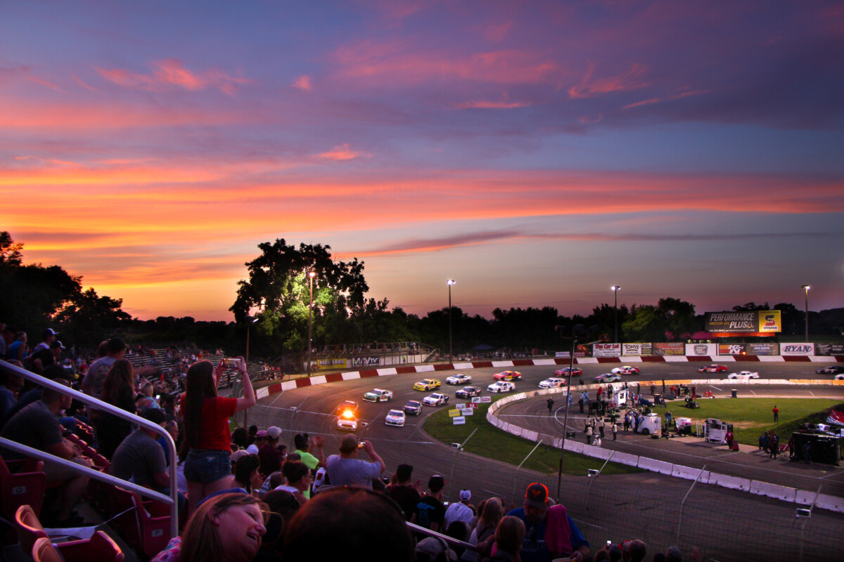 Shot of a vibrant sunset over the Elko Speedway with cars racing on the track in Minnesota. Shot of a vibrant sunset over the Elko Speedway with cars racing on the track in Minnesota.