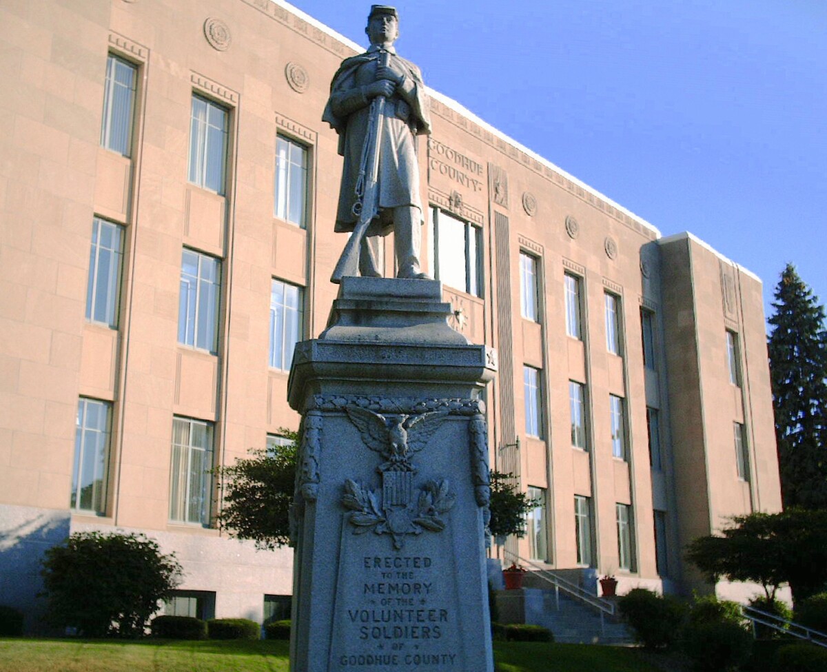 A statue of a soldier in front of the Goodhue County Courthouse with a plaque that reads, "Erected to the Memory of the Volunteer Soldiers of Goodhue County".