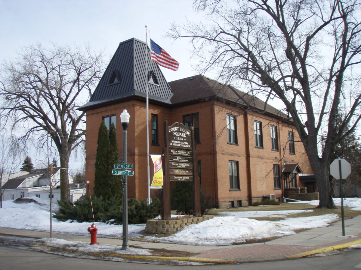 Corner shot of the Isanti County Courthouse with snow on the ground during the day.