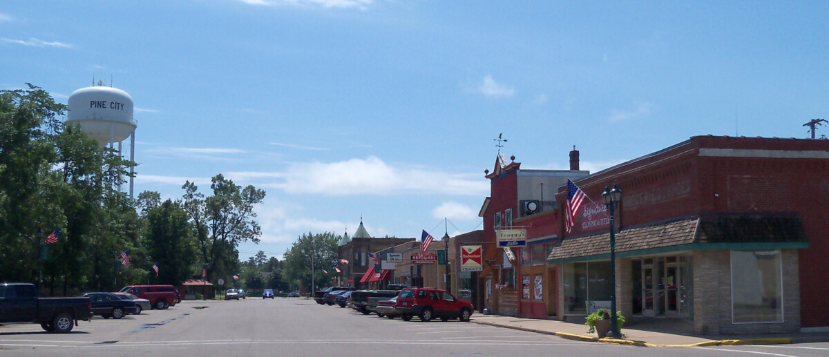 Businesses on a street in Pine City, Minnesota with a water tower in the background during the day. Businesses on a street in Pine City, Minnesota with a water tower in the background during the day.