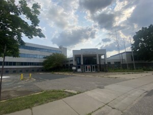 Front view of the former Wright County Government Center in Minnesota, featuring an empty parking lot and overgrown landscaping under a cloudy sky. Front view of the former Wright County Government Center in Minnesota, featuring an empty parking lot and overgrown landscaping under a cloudy sky.