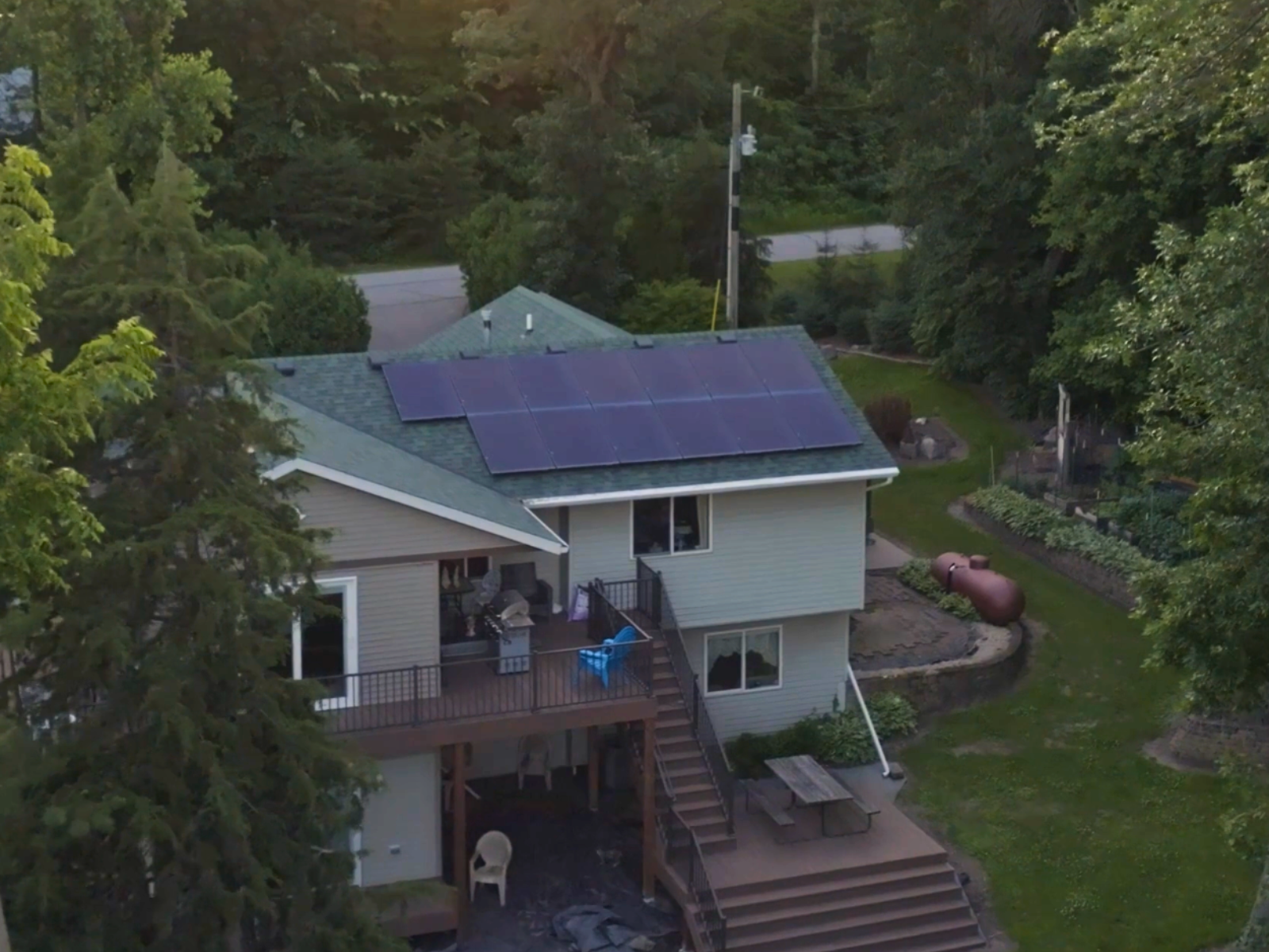 Residential solar panel system installed on upper roof section by Wolf River Electric, surrounded by trees and backyard patio Residential solar panel system installed on upper roof section by Wolf River Electric, surrounded by trees and backyard patio