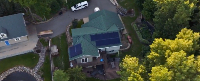 Aerial view of rural home with custom solar panel layout by Wolf River Electric, nestled among trees with visible garden and pond