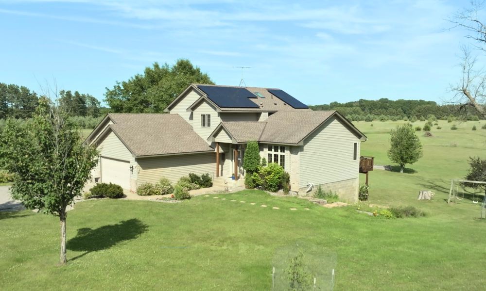 Full front exterior of a rural Minnesota home with rooftop solar panels installed by Wolf River Electric