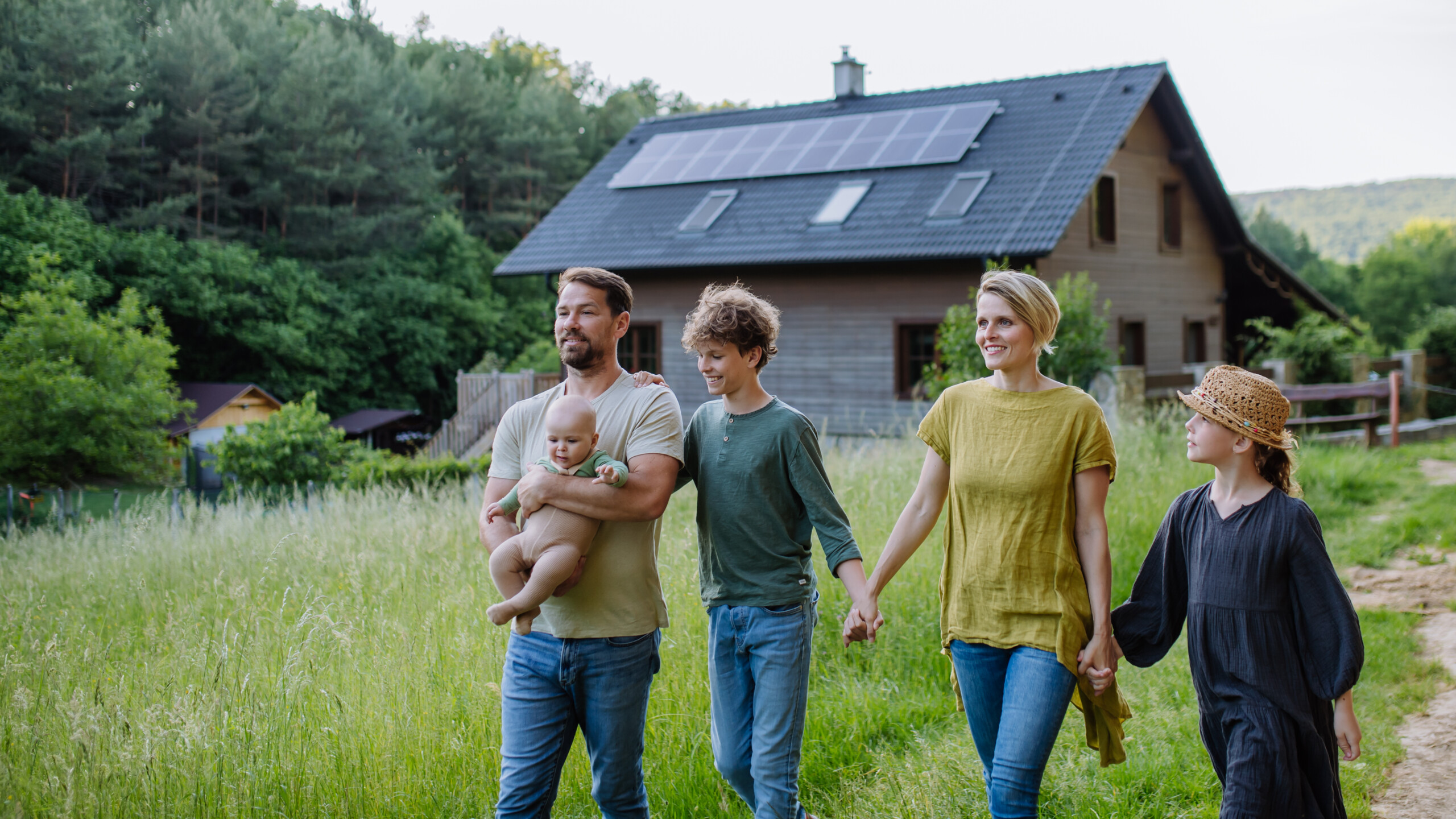 Happy family walking outside their home with rooftop solar panels, showcasing residential solar energy, net metering benefits, and clean energy savings for homeowners