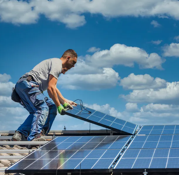 solar-companies-in-north-dakota Technician installing solar panels under a clear blue sky.