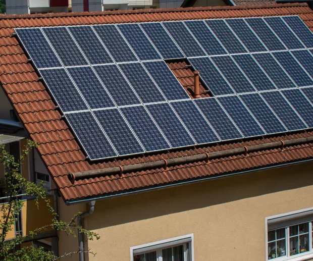 House with solar panels installed on a red-tiled roof.