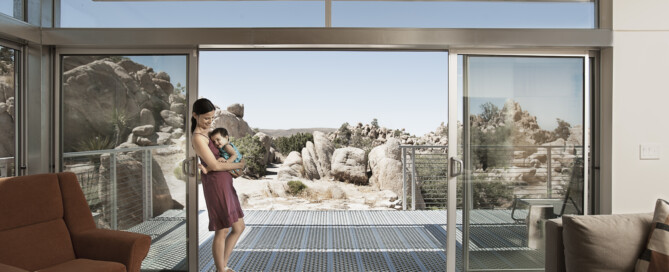 Smart electrical panels managing solar-powered home energy in a modern energy-efficient home with large glass doors overlooking a desert landscape, Wolf River Electric