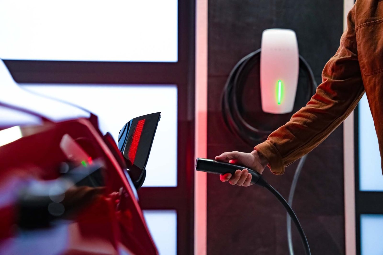 Driver plugging an electric vehicle into a Tesla Wall Connector