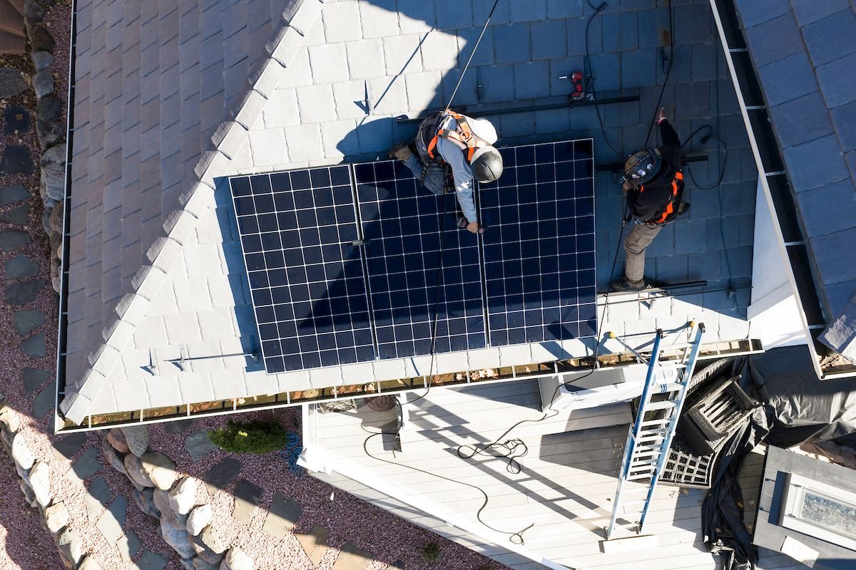 Aerial view of a Wolf River Electric crew working on a roof-mounted solar array