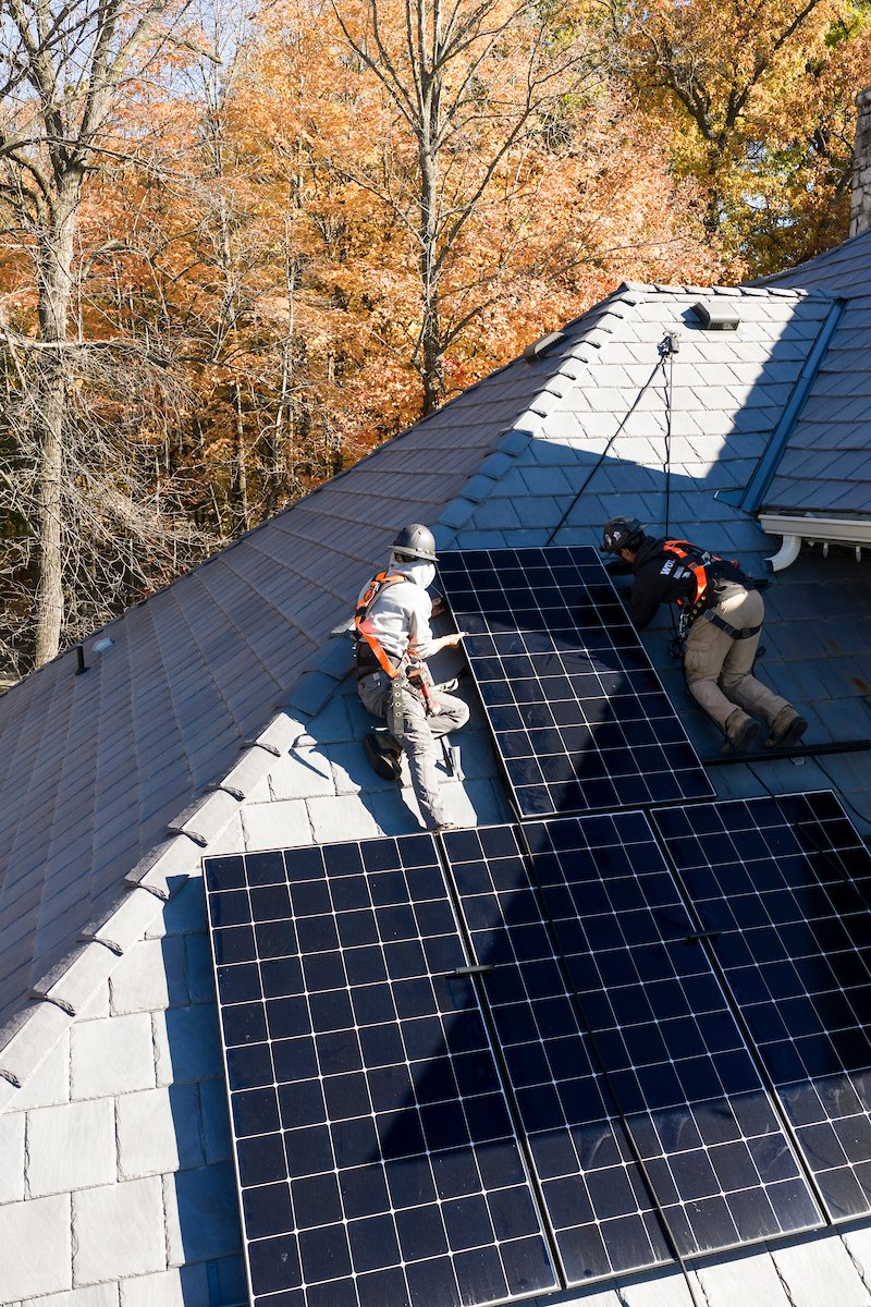 Wolf River Electric crew in hard hats installing solar on a slate roof