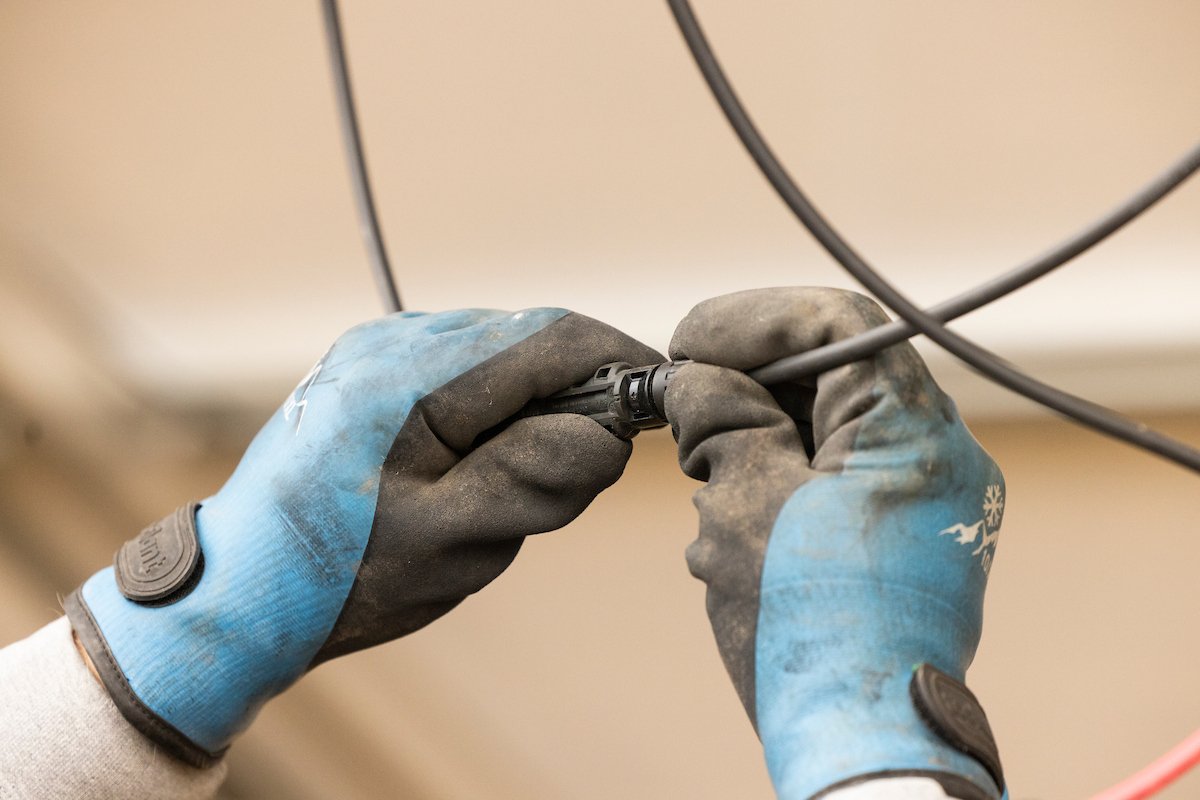 Gloved hands connecting a solar cable, Wolf River Electric electrical work