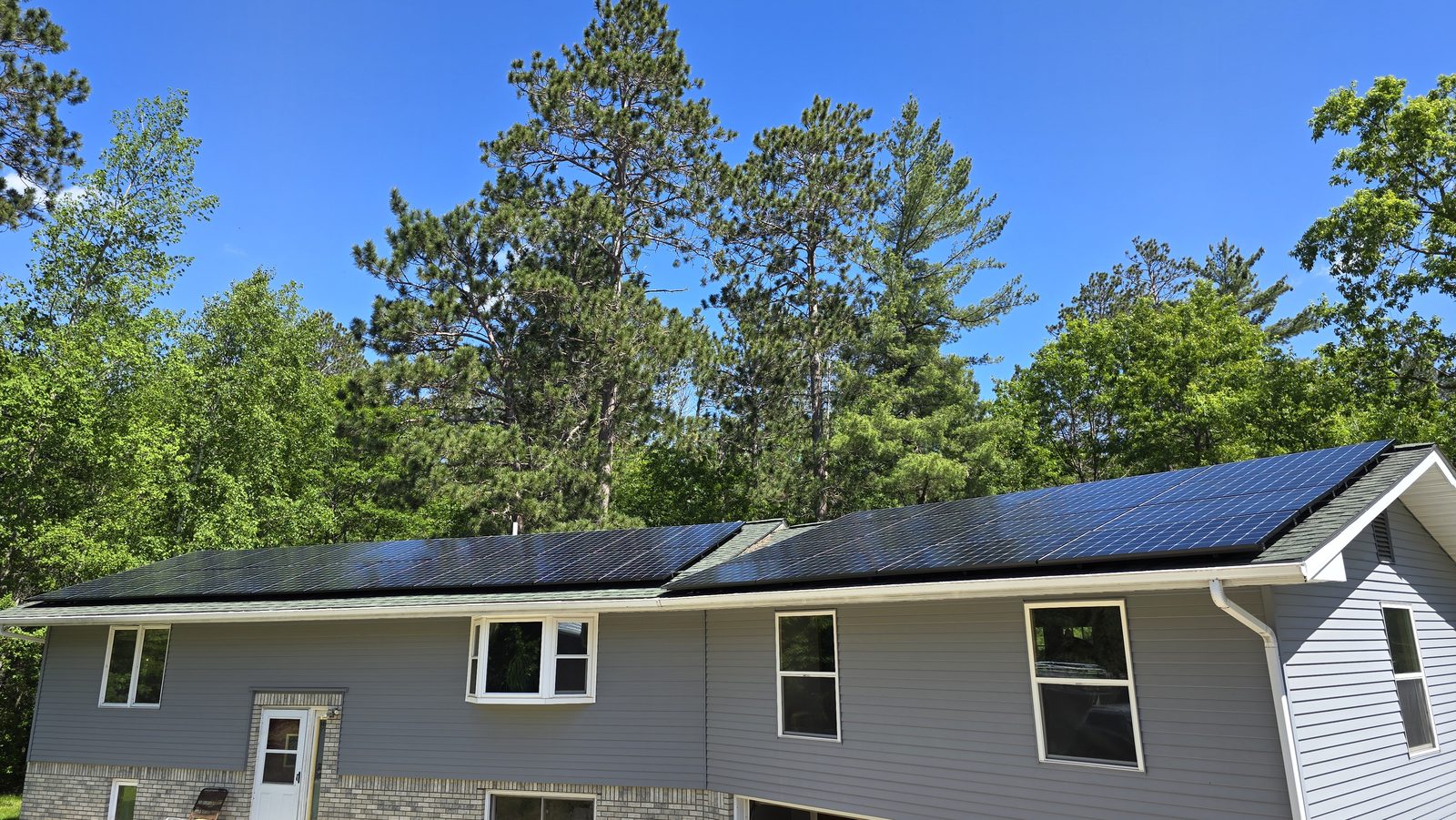 Home with solar among pines, installed by Wolf River Electric