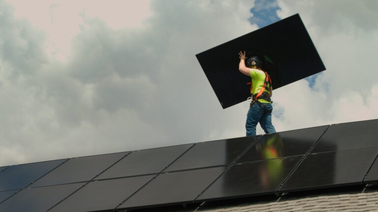 Wolf River Electric installer in a hard hat carrying a solar panel