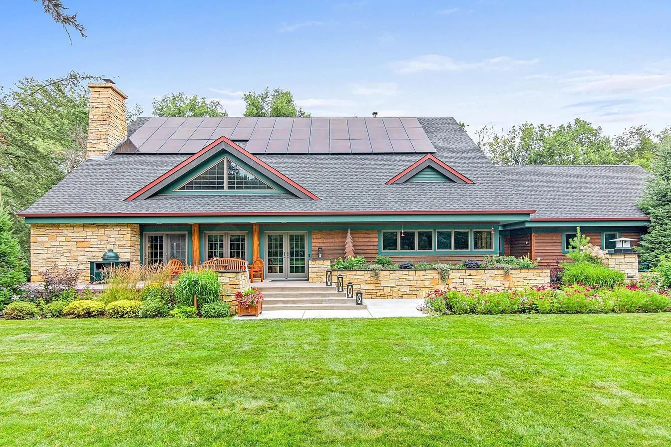 Log and stone home with black solar panels