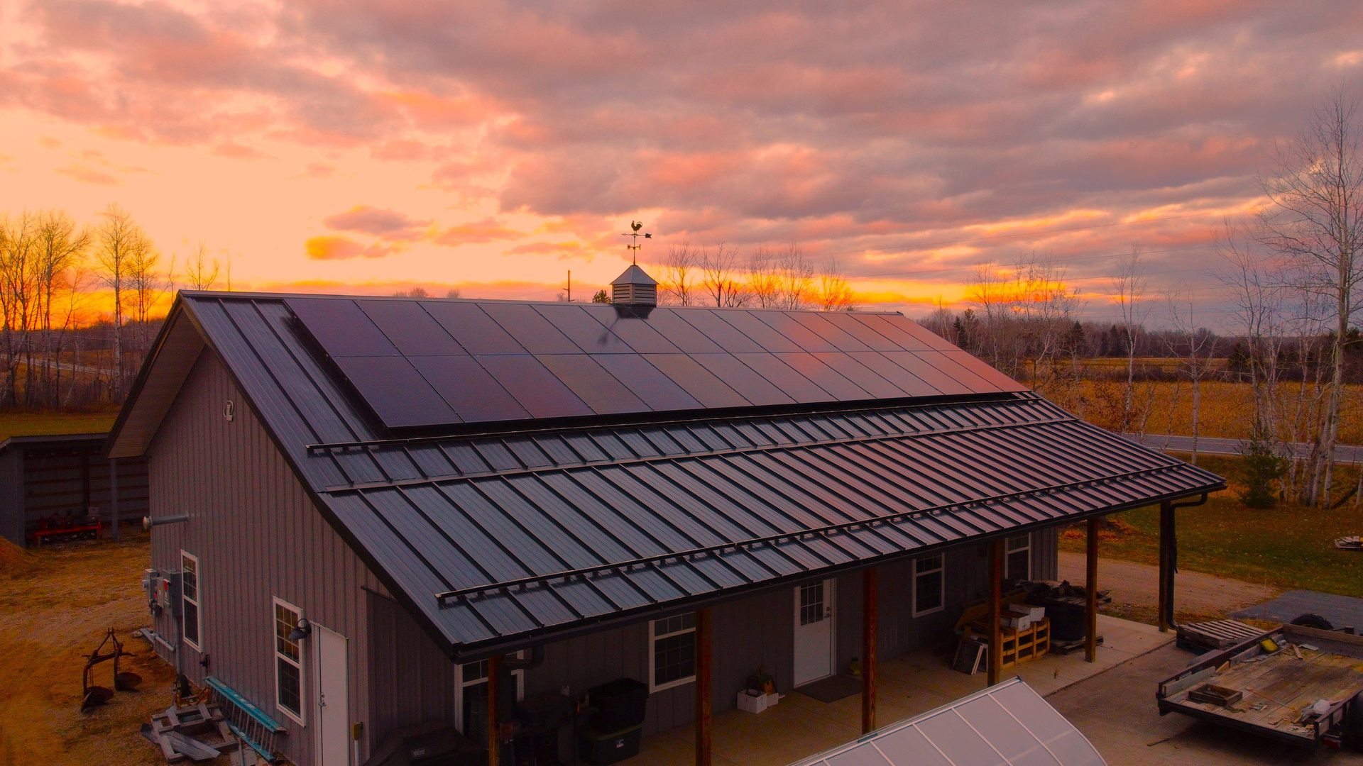 Solar panels on a barn roof at sunset, installed by Wolf River Electric