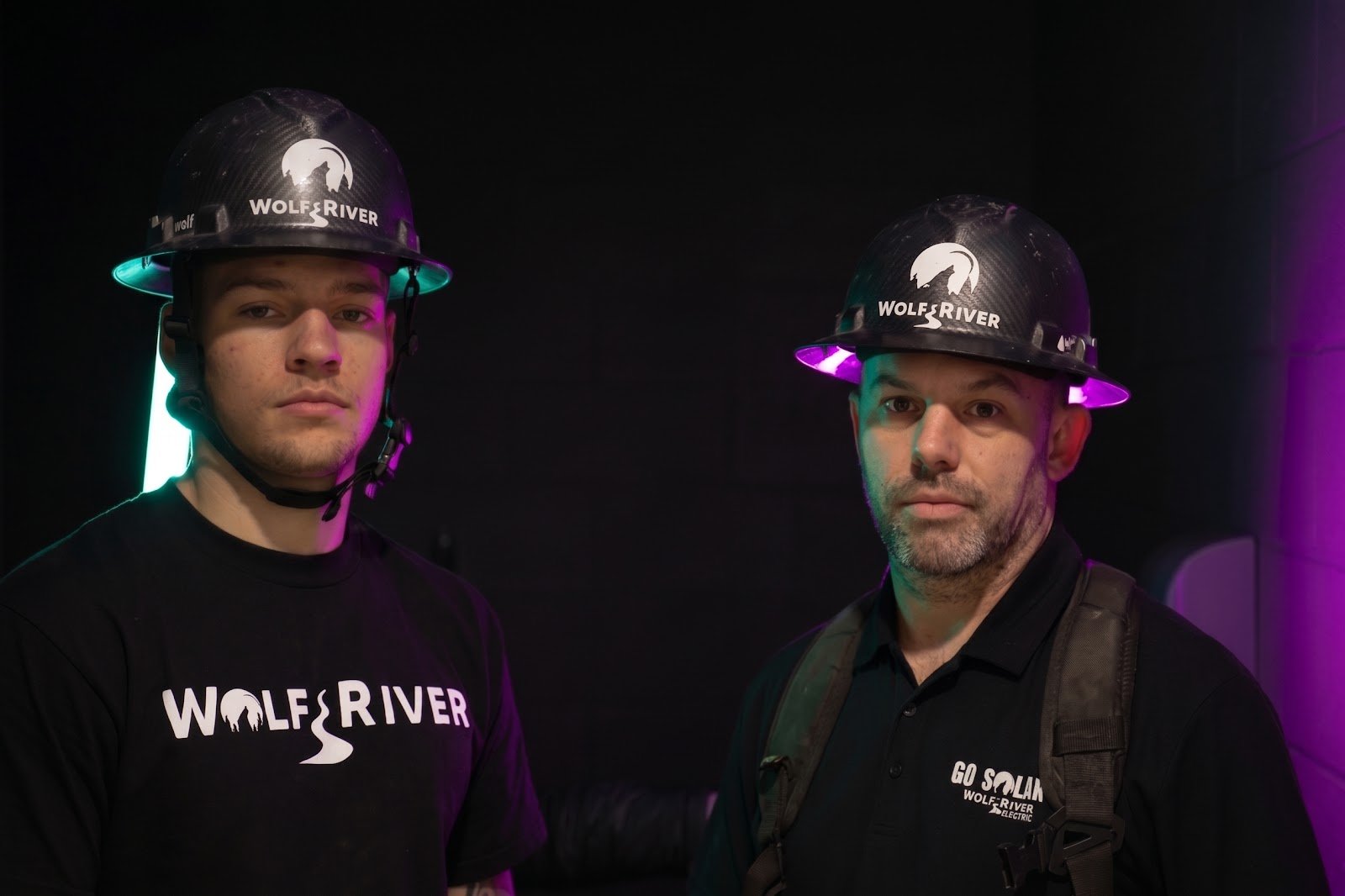 Two Wolf River Electric crew members in branded hard hats