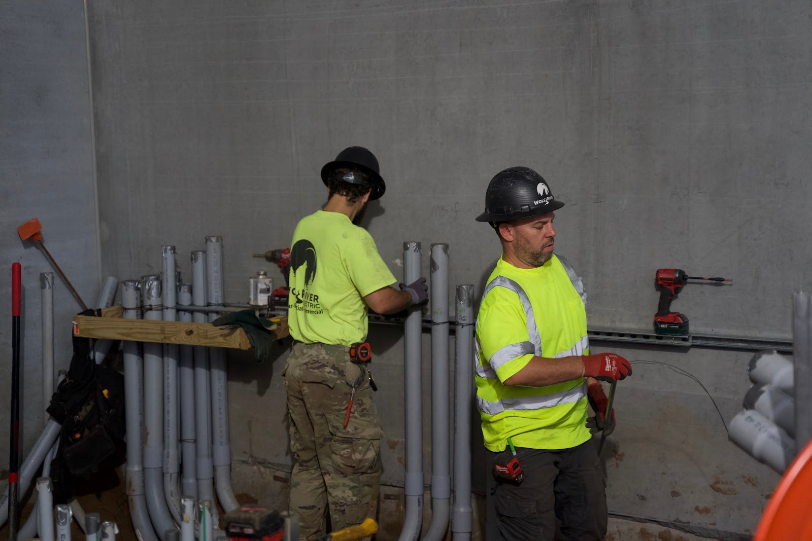 Two Wolf River Electric electricians in hard hats talking on a job site