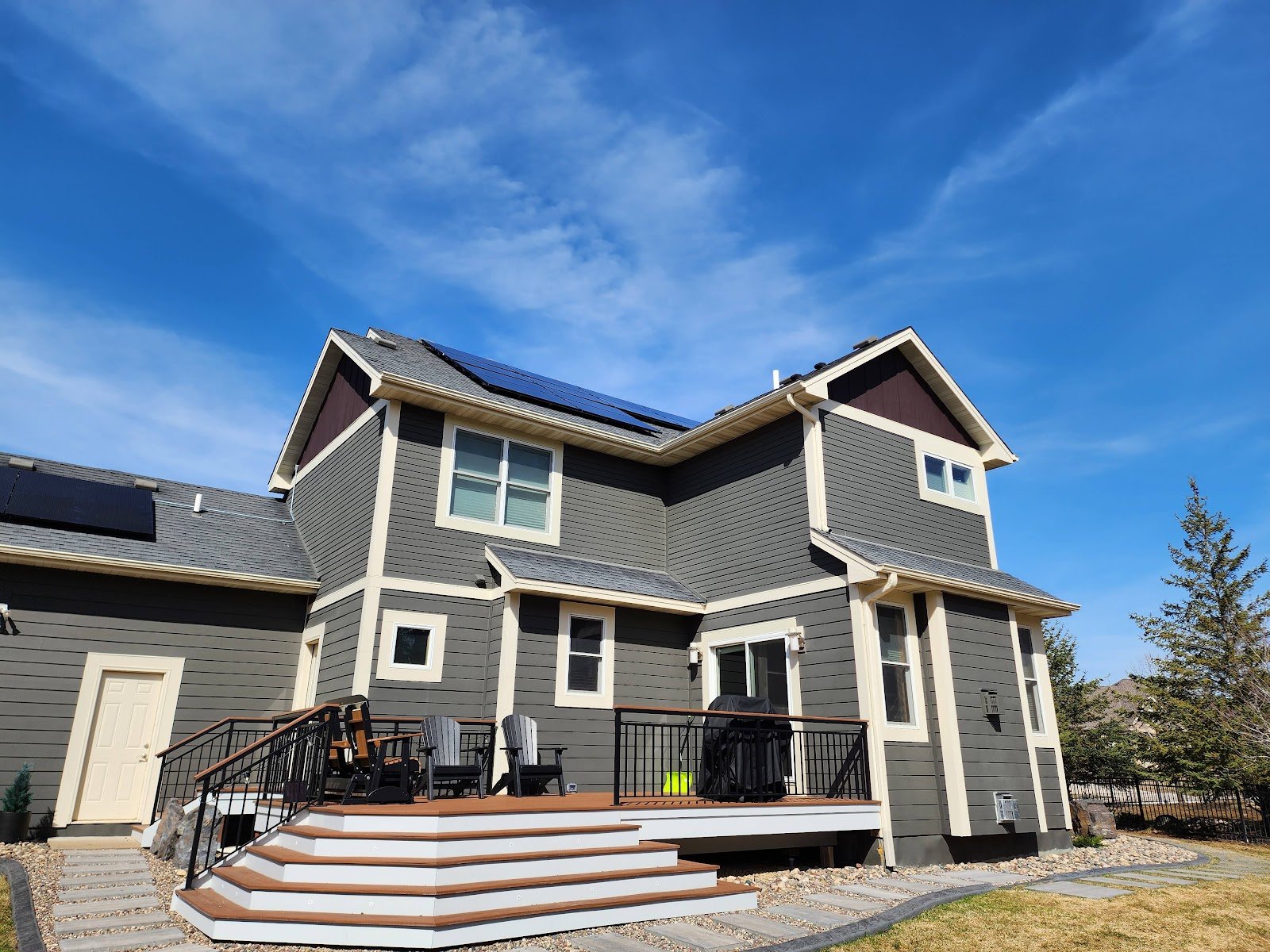 Two story gray home with solar panels, installed by Wolf River Electric