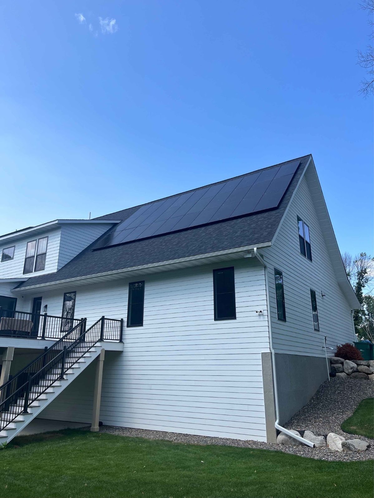 White home with solar panels blue sky, installed by Wolf River Electric
