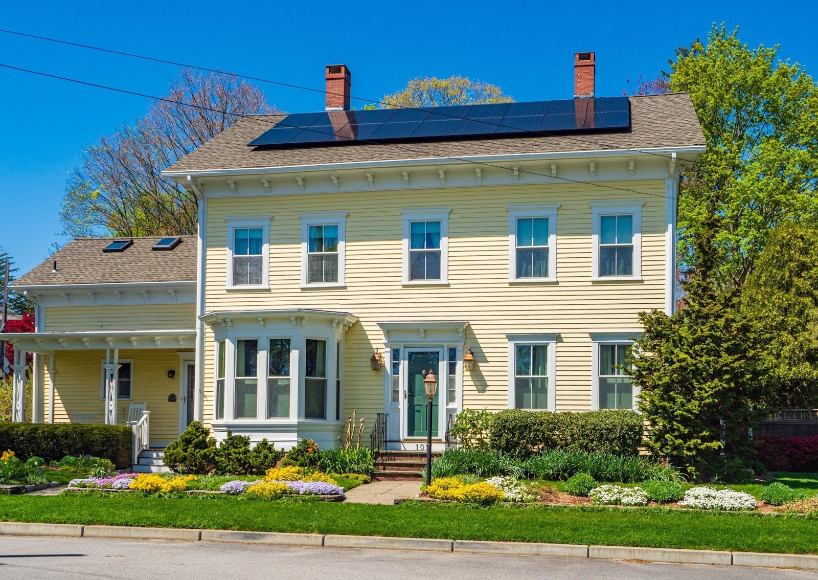 Yellow colonial home with solar panels, installed by Wolf River Electric